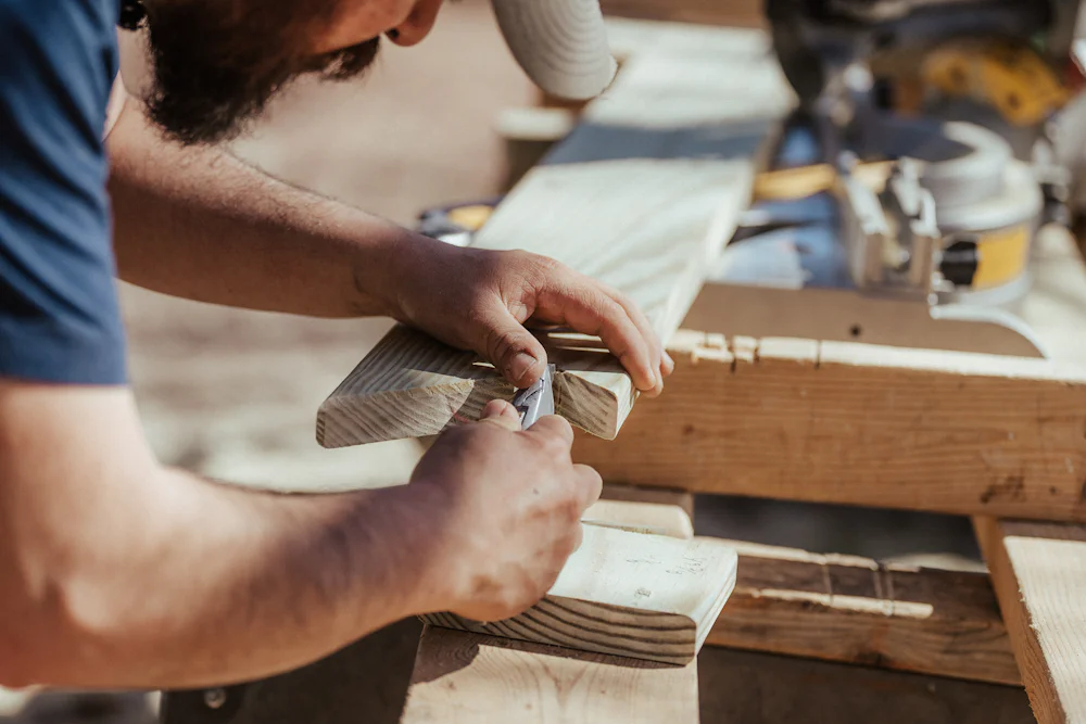 A carpenter shaping a piece of timber with a hand tool
