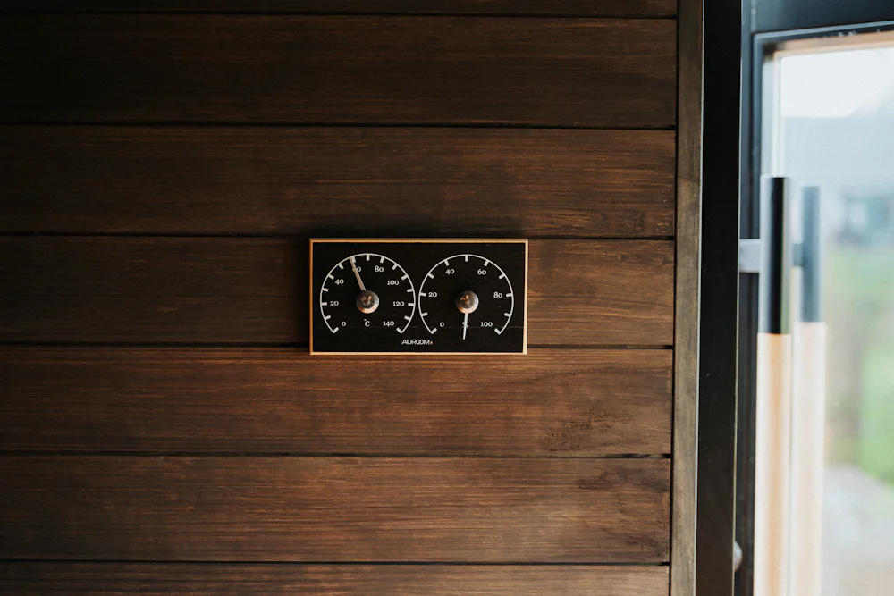 A thermometer and hygrometer on a sauna wall
