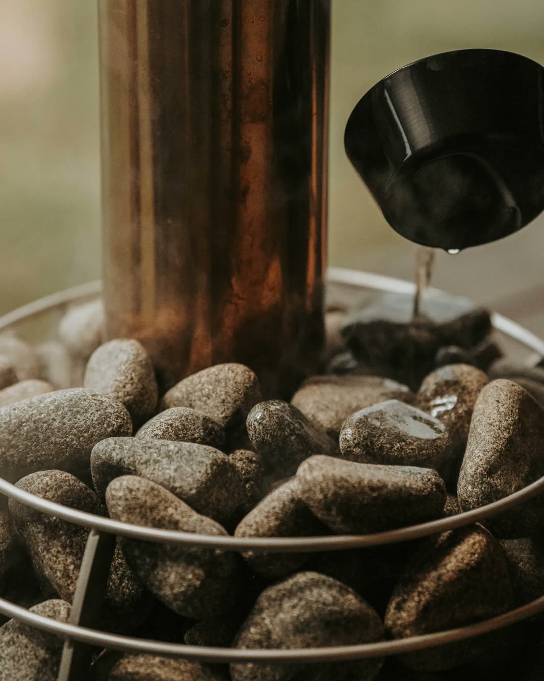 Water pouring from a sauna ladle onto hot stones
